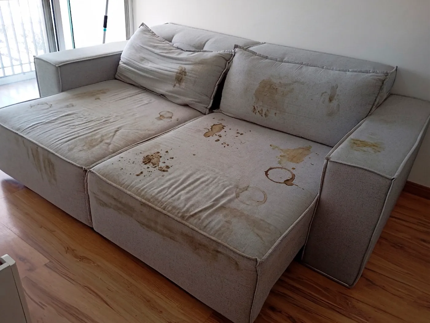 Sofá retrátil antes da higienização, com manchas escuras espalhadas pelos assentos e encostos.