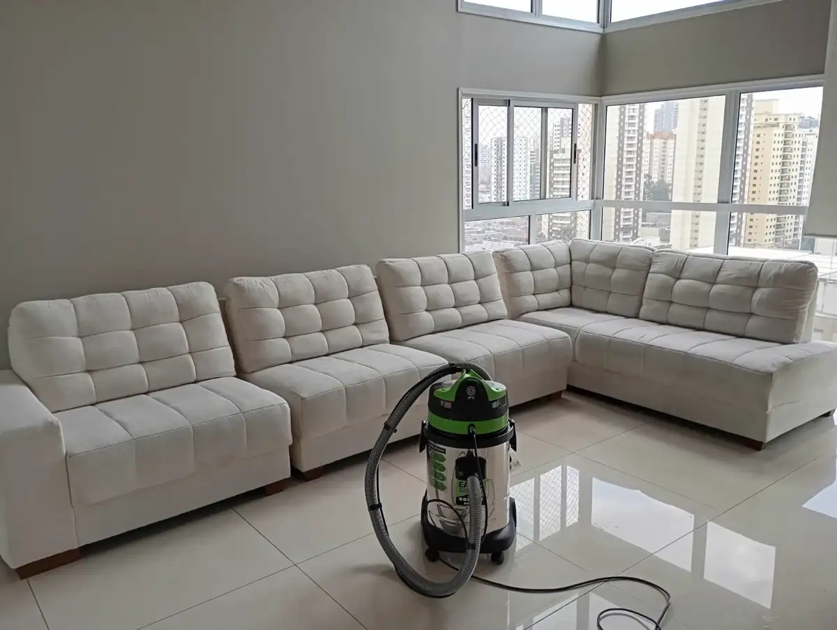 Sofá de canto claro numa sala ampla com vista para a cidade, com a extratora da Perito posicionada ao lado durante o atendimento.